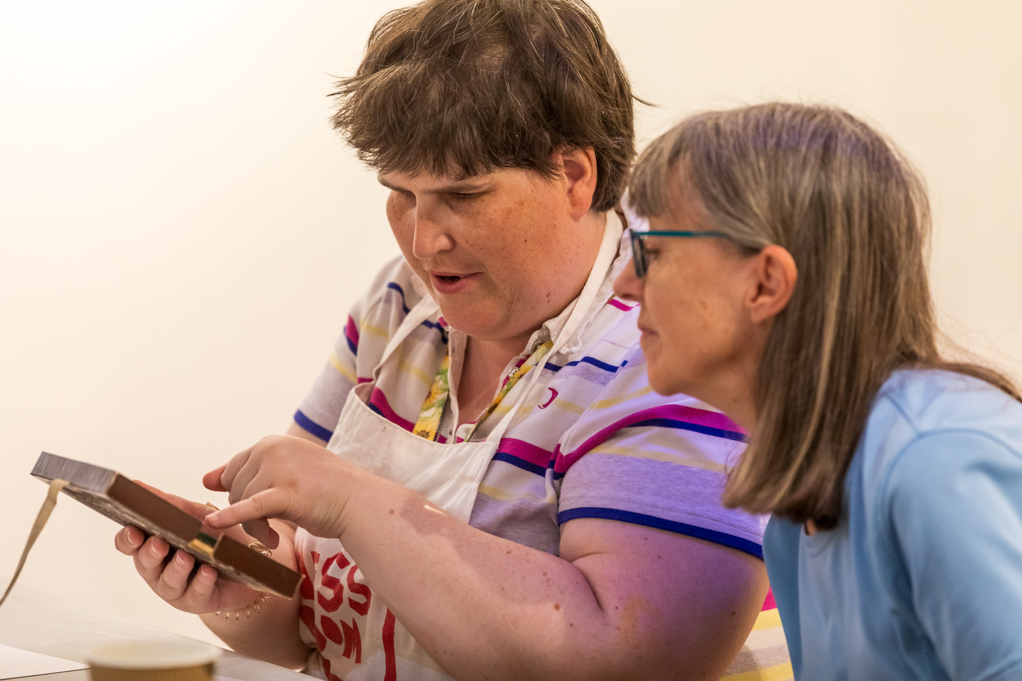 2 members study an artifact using their hands to feel the item